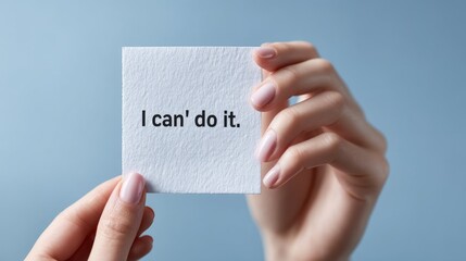 Hands Holding Paper with I Can't Do It Text on Light Blue Background