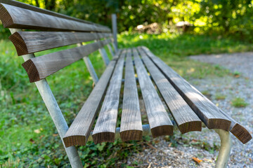 Fototapeta premium Bench in a park with meadow and trees, as viewed from the side. Vanishing point. 