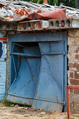 Damaged garage doors after a bomb blast. The metal was bent by the shock wave of the explosion. War in Ukraine