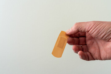Male hand is holding a medical patch. White background, copy space.