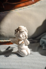 Plaster figurine of a white Angel holding a small zircon gem in his hand with a smile on his face. The character of Angel is childish