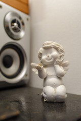 Plaster figurine of a white Angel holding a small zircon gem in his hand with a smile on his face. The character of Angel is childish