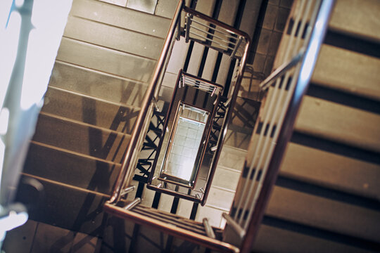 Intricate spiral staircase offers mesmerizing architectural view in Nizhny Novgorod. Captured from above, harsh lighting creates striking shadows, enhancing geometric patterns