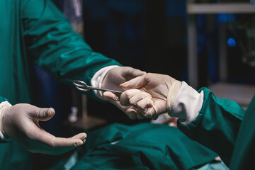 nurse giving professional doctor medical scissors during operating in emergency room. er staff help hand metal equipment scissors to doctor. surgeon get scissors tools to use in procedure from staff