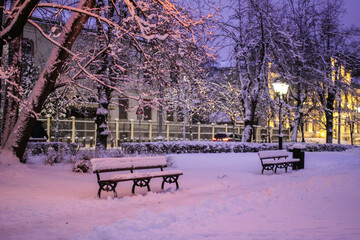 Romantic evening view of snowy park with lanterns in Riga.