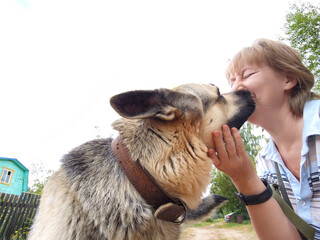 Mature woman shares a joyful moment with her German Shepherd in a scenic outdoor setting