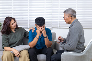 Asian senior counselor and couple sitting together with man expressing frustration during therapy session, work crisis pressure and professional failure, mental health support, relationship guidance