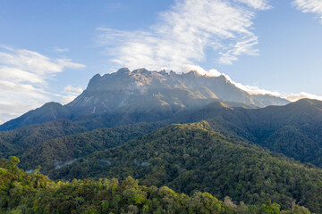 Scenic aerial landscape of Mount Kinabalu, the highest peak in Malaysia, with green valleys below.
