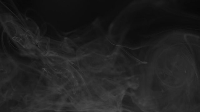 Ethereal smoke or mist drifting on black background. Seamless video footage for overlay effects in post-production and creative projects.