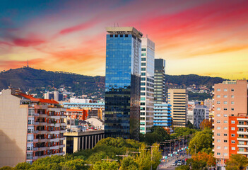 Modern skyline view of city buildings at sunset with vibrant colors, distant hills. Stunning view...