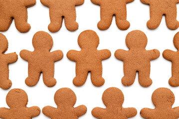 Gingerbread men cookies in a repetitive pattern on a white background, symbolizing baking, holidays, and sweet treats.