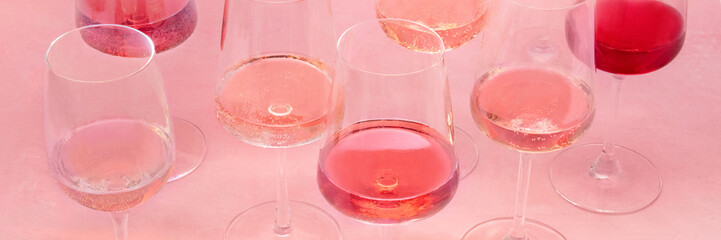 Rose wine panorama, a variety of hues and tints, on a pink background, many wine glasses