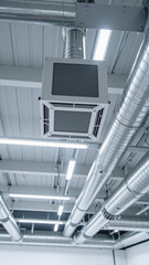 Ceiling air conditioning unit with metallic ducts in modern industrial space, showcasing clean and functional design