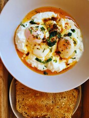 Healthy breakfast with poached eggs on yogurt, herbs, and whole grain toast