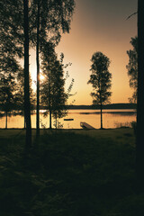 Romantic sunset on the lake with boat, jetty and forest silhouettes