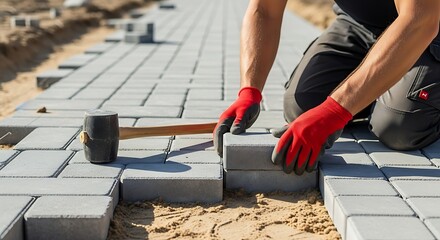Construction worker laying interlocking concrete pavers for a new pathway