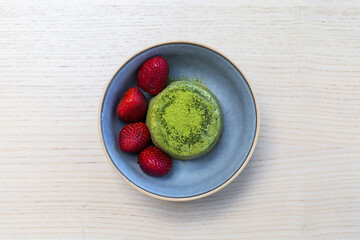 A bowl of matcha cake with strawberries.
