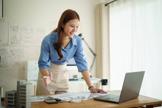 Smiling female architect presenting building project plans during an online meeting. - Powered by Adobe