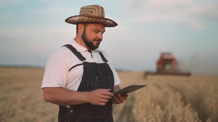 Modern agriculture and agribusiness, portrait of farmer with tablet in fields, harvester-combine picking crops in farmland, agronomist using tablet with software for agronomy and bioengineering