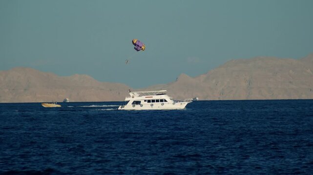 Ships and speedboat with parachute parasailing on the Red Sea near Tiran Island.