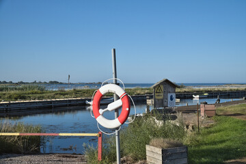 Lifebuoy at the small harbor with a view of the water and coastal landscape