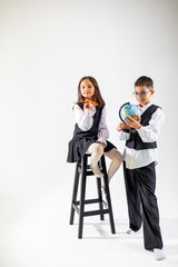 Obraz premium Two children, a girl and a boy, dressed in formal attire, exploring their creativity and curiosity about the world.