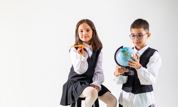 Two diverse children, a girl with brown hair and a boy with glasses, explore geography with a globe and paper plane. - Powered by Adobe