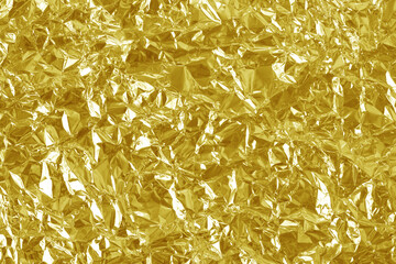 Shiny gold foil texture background, pattern of yellow wrapping paper with crumpled and wavy.