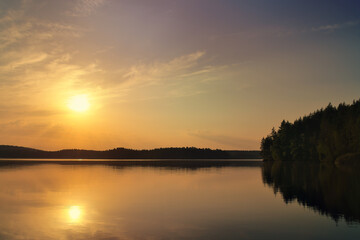 Sunset at the lake with reflection and forest, peaceful evening atmosphere
