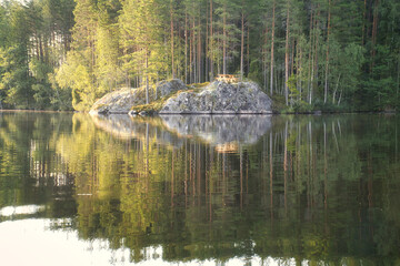 Lake landscape with a rocky island and a picnic table, surrounded by forest