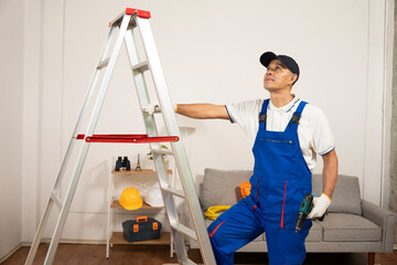 Maintenance professional with ladder: a diligent maintenance worker dressed in overalls stands beside a sturdy ladder, focused on the task at hand.