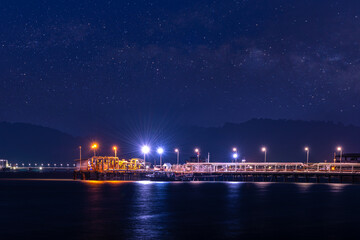 Fototapeta premium night scene of Oil ship tanker ship load or unload oil at loading dock from refinery for transportation on the sea