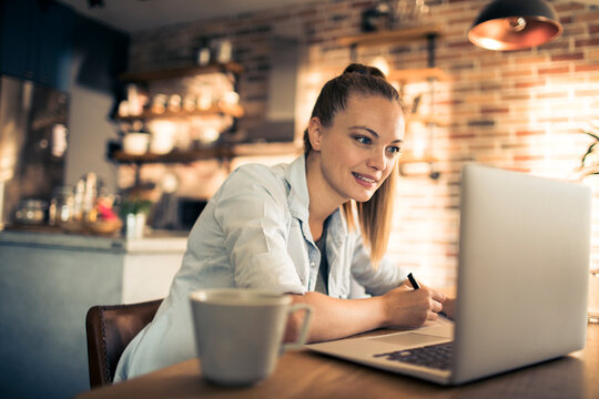 Woman working on laptop in cozy kitchen