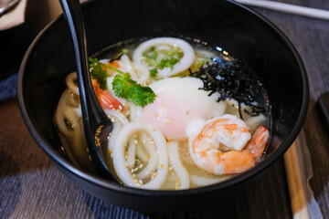 Close-up of the udon with seafood squid, prawn and egg. Japanese Cuisine. Food and beverage concept. Food background.