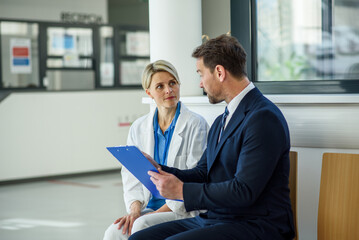 Pharmaceutical sales representative introducing new medication to female doctor.