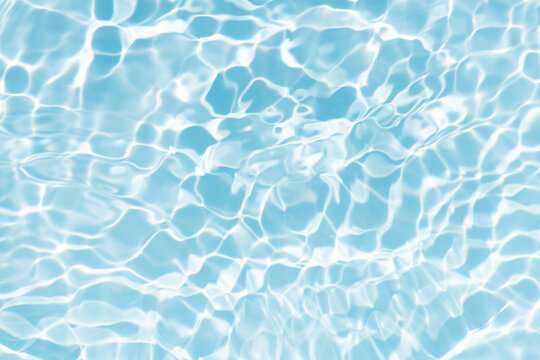 Blue water with ripples on the surface. Defocus blurred transparent blue colored clear calm water surface texture with splashes and bubbles. Water waves with shining pattern texture background.