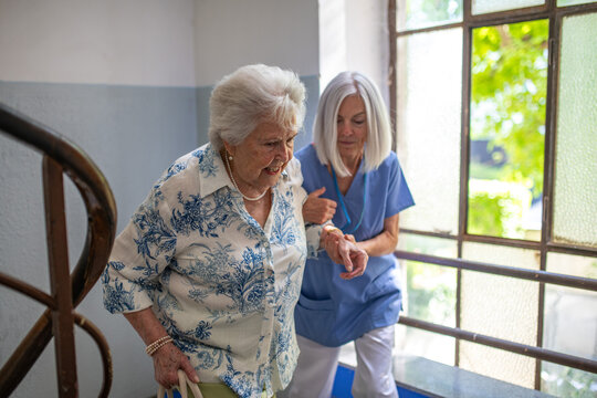 Female healthcare worker helping senior patient walking up the stairs.