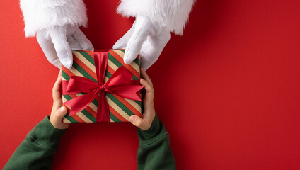 Santa handing a red ribbon gift to a child during Christmas season