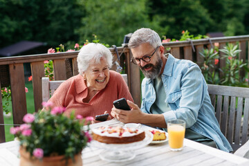 Mature son spending time with elderly mother, drinking coffee and talking.