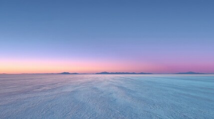 A tranquil landscape at dawn featuring a smooth expansive terrain resembling salt flats contrasting with distant mountai