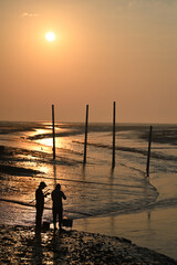 The golden out of the sea under the morning sun and fishing people