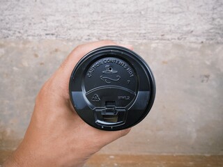 Hand holding a cup of coffee in disposable or take away packaging