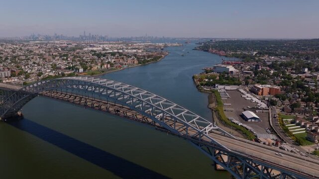 Aerial drone footage of the Bayonne Bridge spanning the Kill Van Kull waterway with Bayonne New Jersey on one side and Staten Island New York on the other and Manhattan skyline in the distance ProRes 