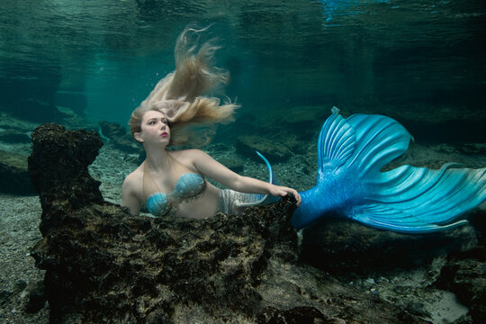 Woman dressed in a mermaid costume underwater lying on the seabed