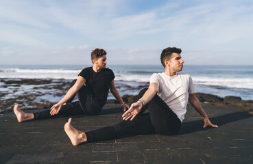 Two men in seated spinal twist engage opposite focus, embodying dual clarity and structured detachment as mindful tools to counteract digital distraction and routine fragmentation.