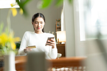Young Asian woman enjoying a peaceful moment reading a book near window. Calm lifestyle, self-learning, and mindfulness at home.