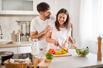 In a sunlit kitchen, a couple shares laughter and joy as they prepare a healthy meal.
