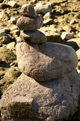 Balancing stones stacked in a pyramid on a dry rocky riverbed. A symbol of balance, calmness, and meditation in harmony with nature and silence.