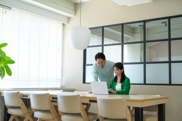 カジュアルな服装でオフィスで仕事をする日本人男女