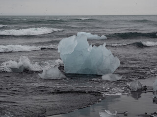 block of ice on black and volcanic sand
